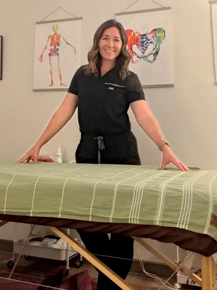 Megan in her treatment room, hands on the treatment table